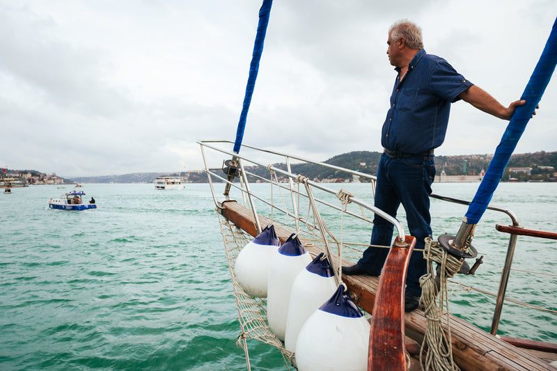 Boat fenders and buoys hanging on a rail with man standing on bow of a Gulet boat in Turkey