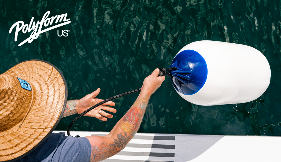 Man in straw hat holding rope fender line attached to white and blue Polyform US boat fender above water