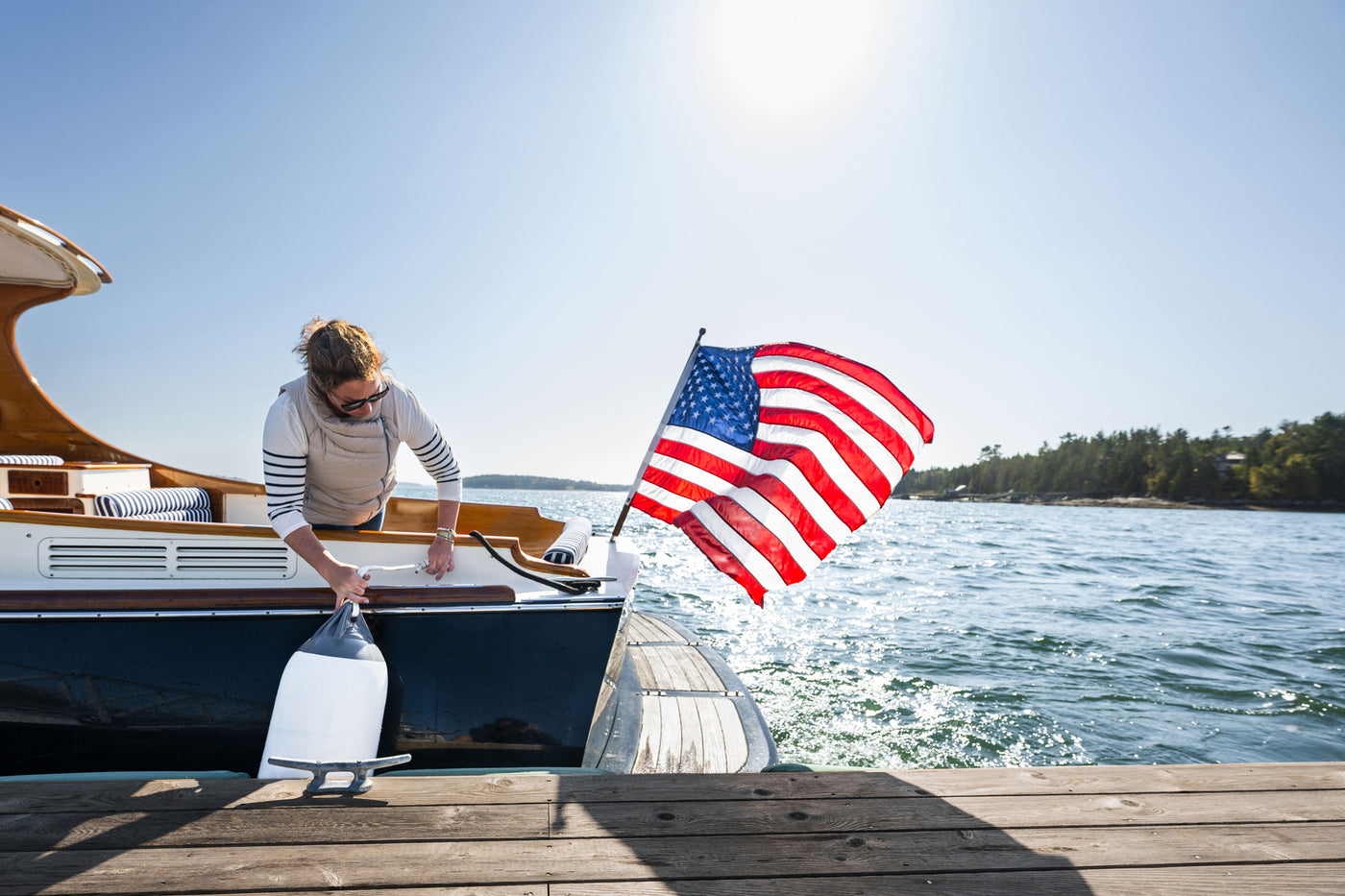 Boat Fender, white with a grey top, against the dock on a classic motor yacht