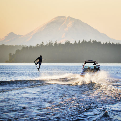 Water skier jumping over wake in Seattle, USA with Mount Rainier in background